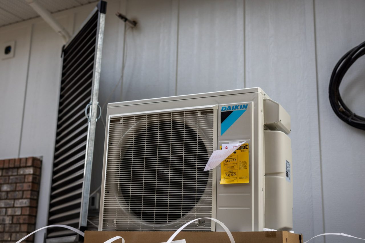 A newly installed Daikin air source heat pump beside the house it heats.