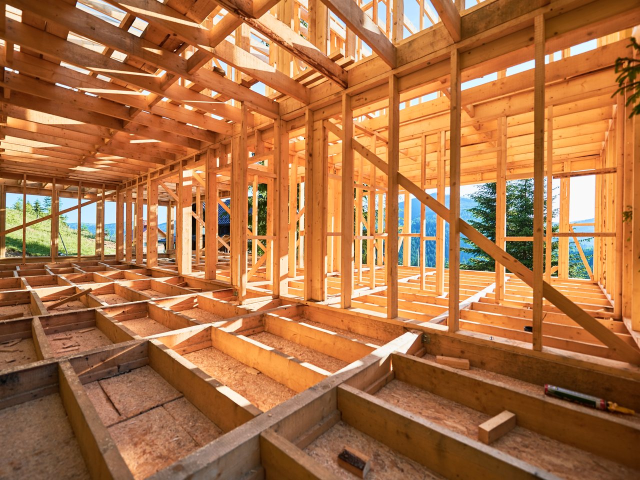 The timber frame of a new house on a mountainside, joists and studs still open to the view before the walls go on.